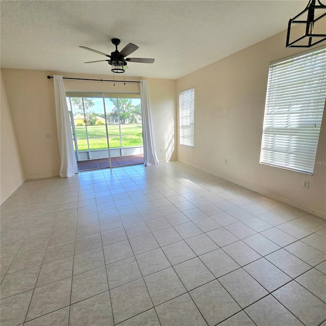 empty room featuring ceiling fan, a textured ceiling, and light tile patterned flooring