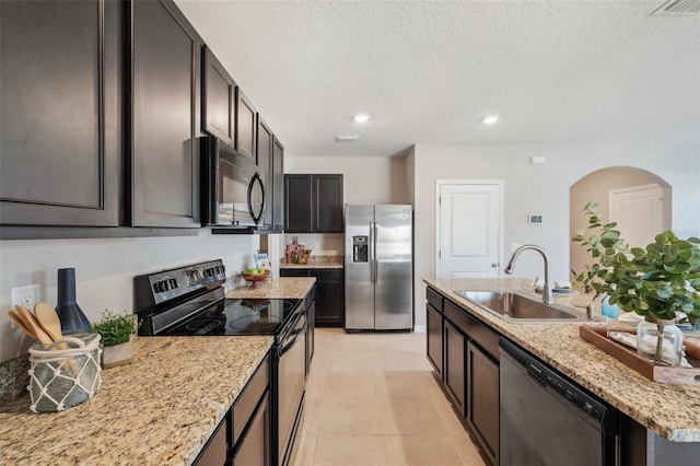 kitchen featuring sink, dark brown cabinets, black appliances, light stone countertops, and light tile patterned flooring