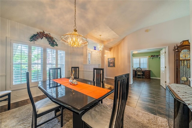 dining space featuring a chandelier, dark tile patterned flooring, and lofted ceiling