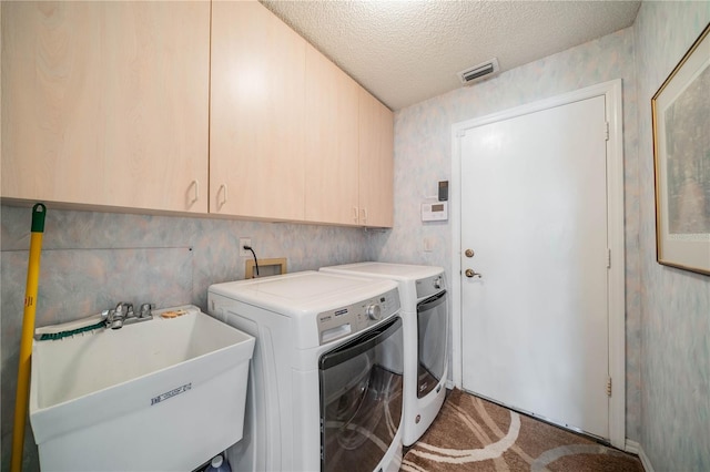 laundry area with cabinets, sink, a textured ceiling, and separate washer and dryer