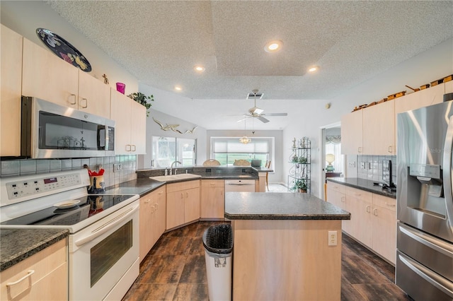 kitchen with a kitchen island, appliances with stainless steel finishes, a textured ceiling, and backsplash