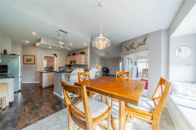 dining space with ceiling fan with notable chandelier and a textured ceiling