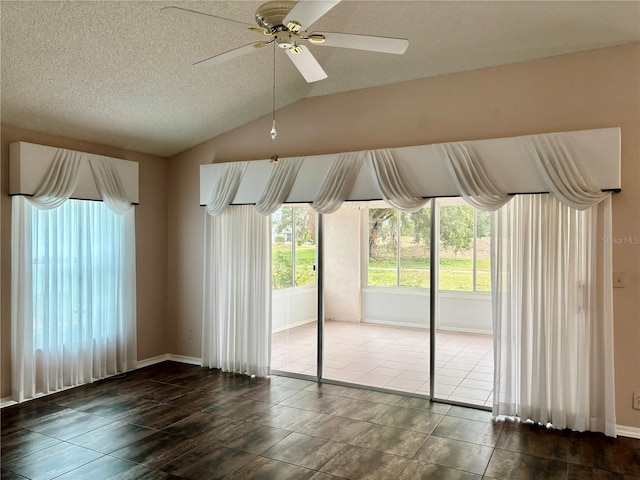 empty room with ceiling fan, plenty of natural light, a textured ceiling, and lofted ceiling