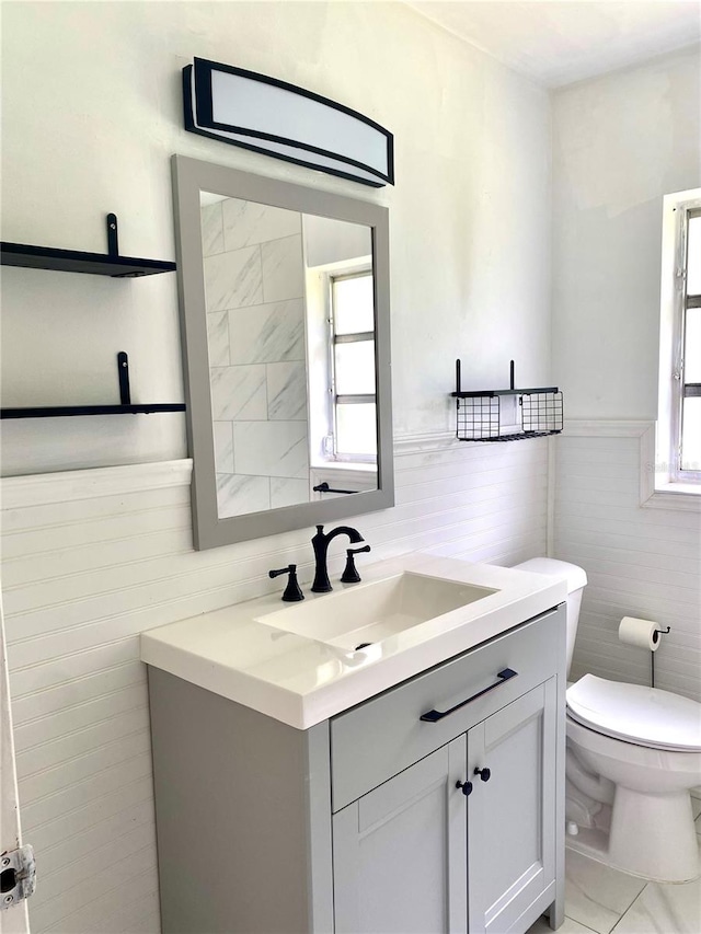 bathroom featuring tile walls, vanity, and toilet