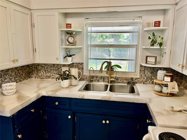 kitchen with blue cabinetry, backsplash, sink, and white cabinetry