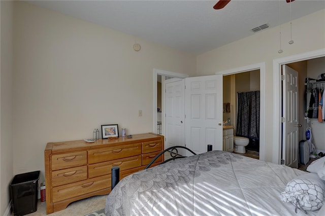 carpeted bedroom featuring ensuite bath, ceiling fan, and a closet