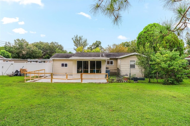 back of property with a yard, a patio area, and a sunroom