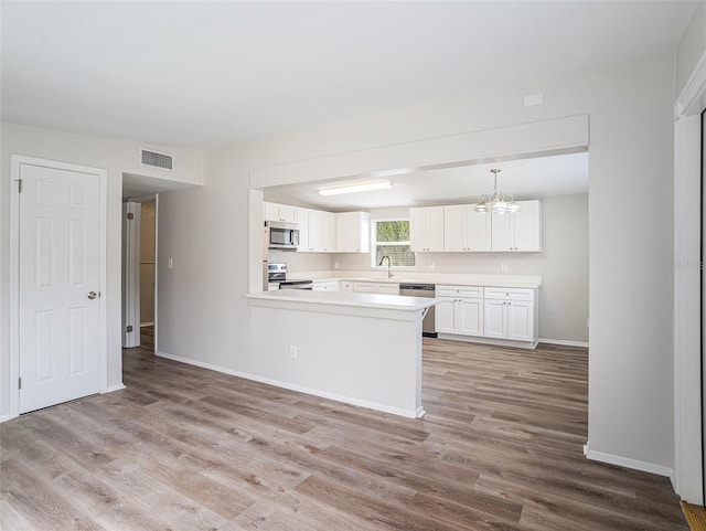 kitchen featuring light hardwood / wood-style floors, kitchen peninsula, stainless steel appliances, and white cabinets