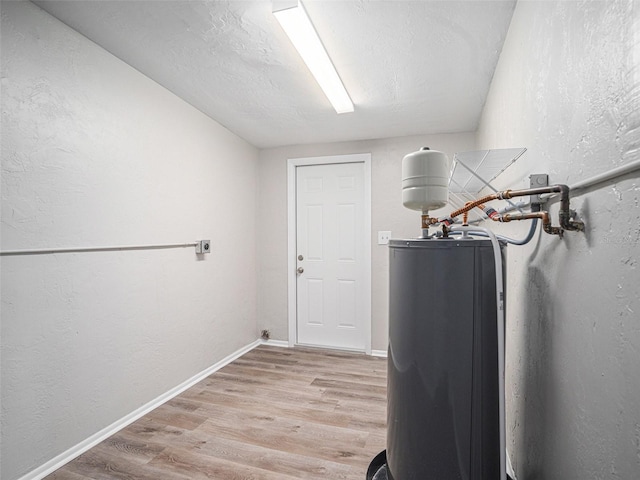 laundry room with hookup for an electric dryer, water heater, and light hardwood / wood-style floors