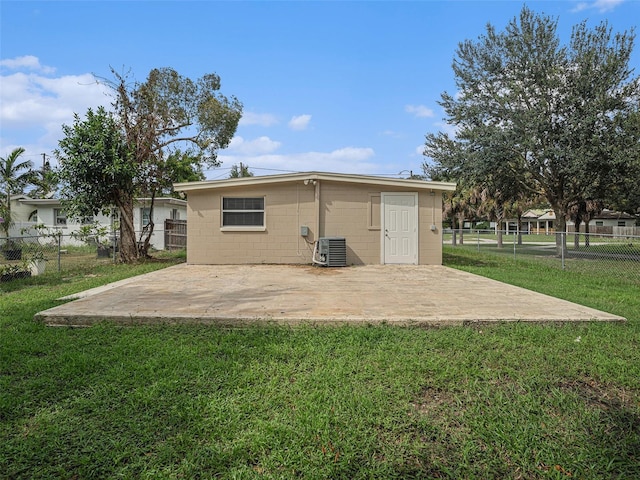 back of property with a lawn, central AC unit, and a patio area