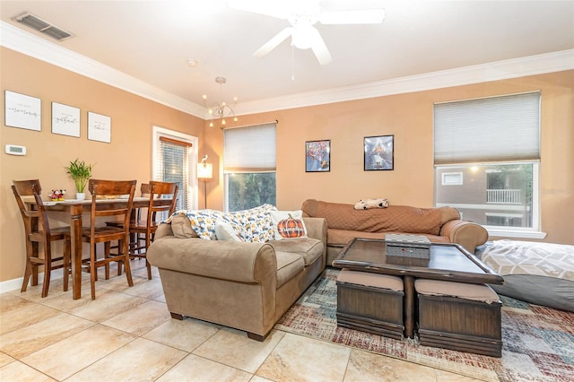 tiled living room with ceiling fan with notable chandelier and ornamental molding