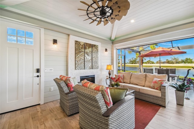 living room featuring a wealth of natural light, ceiling fan, light wood-type flooring, and a fireplace