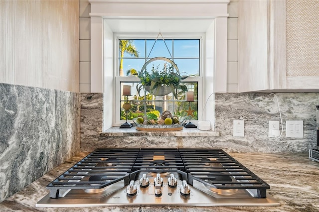 room details featuring stainless steel gas stovetop, light brown cabinetry, and tasteful backsplash