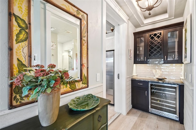 bar with wine cooler, light hardwood / wood-style flooring, stainless steel refrigerator, a tray ceiling, and decorative backsplash