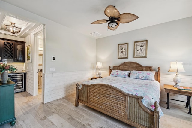 bedroom featuring ceiling fan, wine cooler, and light wood-type flooring