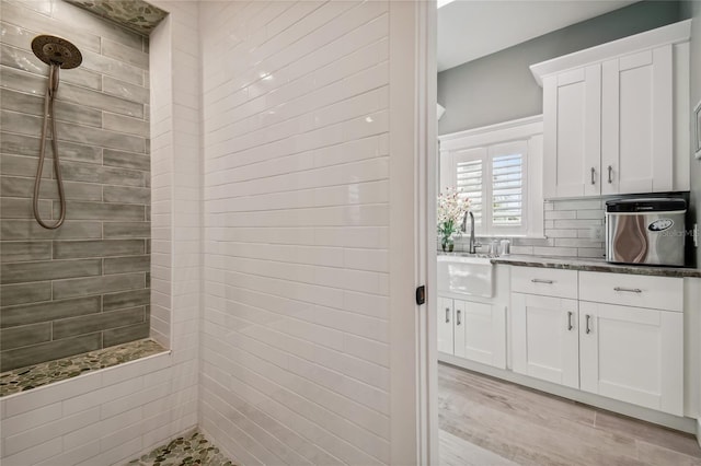 bathroom with a tile shower, vanity, and wood-type flooring