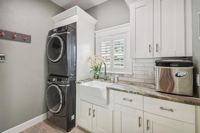 clothes washing area featuring light tile patterned floors, stacked washer and clothes dryer, cabinets, and sink