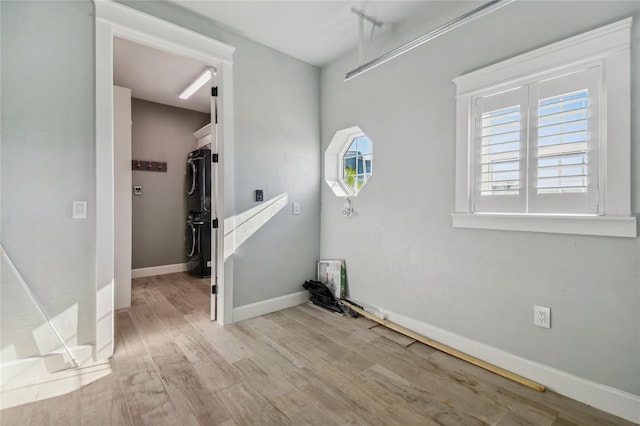 spare room with stacked washer / dryer and light hardwood / wood-style flooring