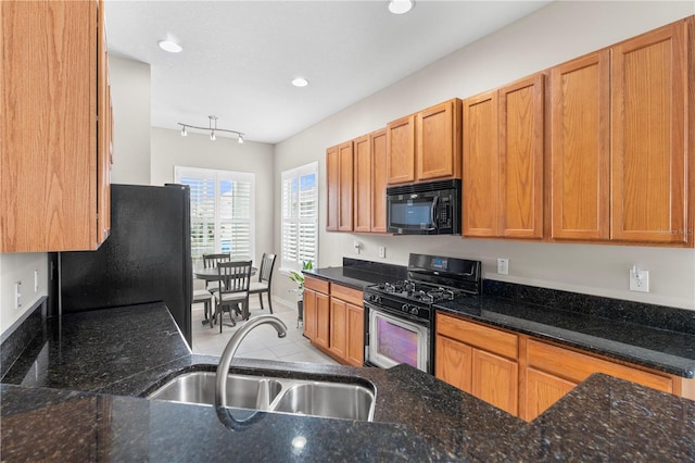 kitchen with sink, dark stone counters, light tile patterned floors, and black appliances