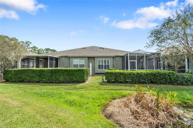 rear view of house featuring a lawn and a sunroom