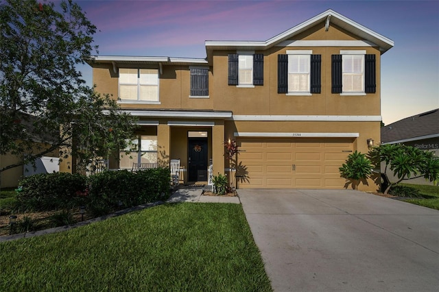 view of front of home with stucco siding, driveway, a garage, and a yard