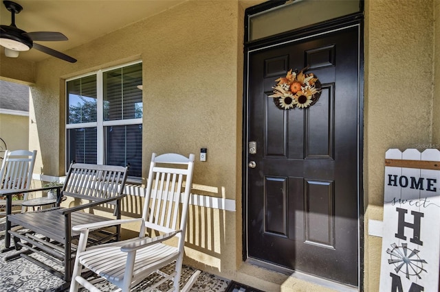 property entrance with stucco siding, a porch, and a ceiling fan