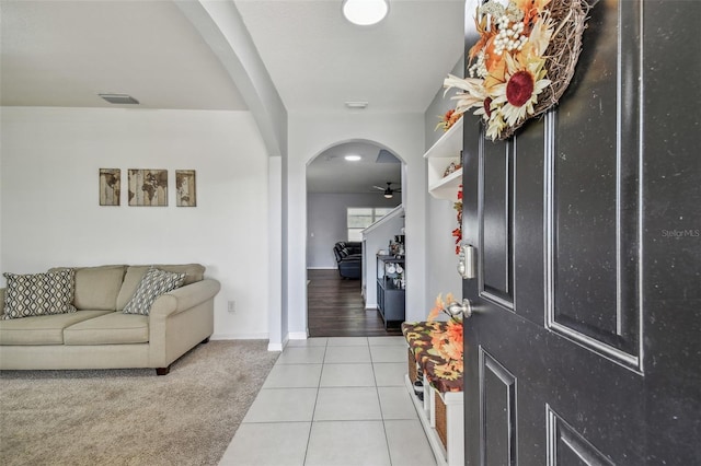 entryway featuring light tile patterned floors, baseboards, arched walkways, visible vents, and ceiling fan