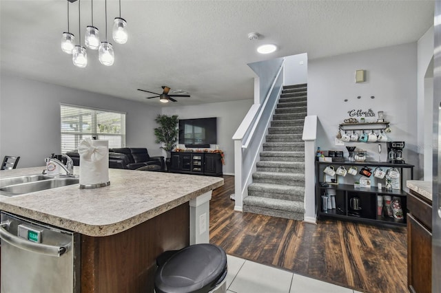 kitchen with ceiling fan, an island with sink, sink, dishwasher, and dark hardwood / wood-style floors