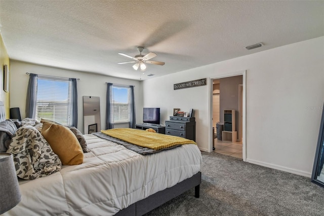 bedroom featuring ceiling fan, carpet floors, connected bathroom, and a textured ceiling