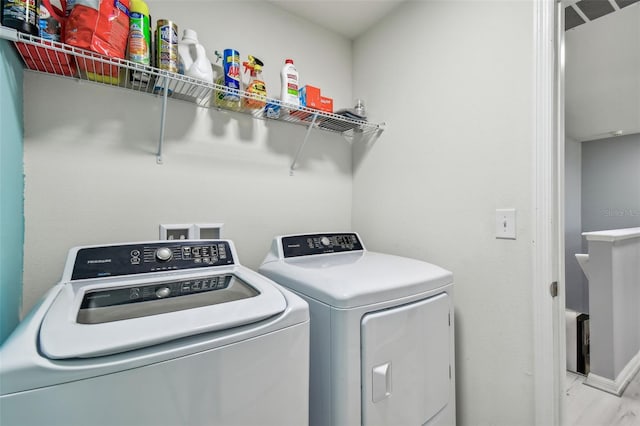 clothes washing area with laundry area, baseboards, and separate washer and dryer