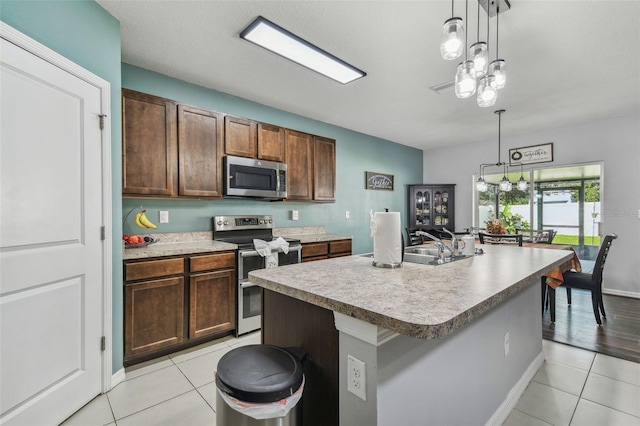kitchen with light countertops, light tile patterned floors, stainless steel appliances, and hanging light fixtures