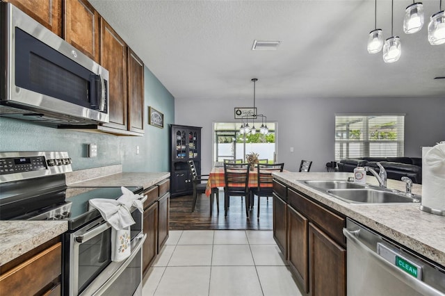 kitchen with appliances with stainless steel finishes, hanging light fixtures, sink, and a chandelier