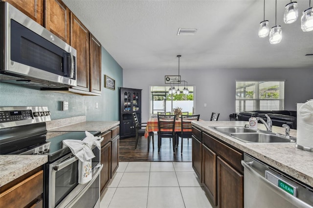 kitchen with light countertops, a sink, light tile patterned flooring, visible vents, and appliances with stainless steel finishes