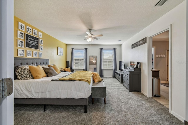 bedroom featuring a textured ceiling, ceiling fan, and light carpet