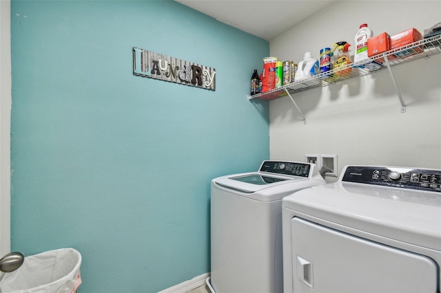 clothes washing area featuring baseboards, washing machine and dryer, and laundry area