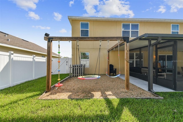 back of house with a fenced backyard, a sunroom, stucco siding, and a yard