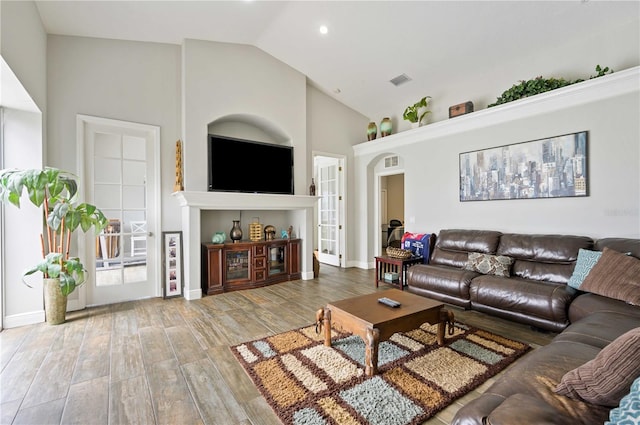 living room with high vaulted ceiling, french doors, and hardwood / wood-style flooring