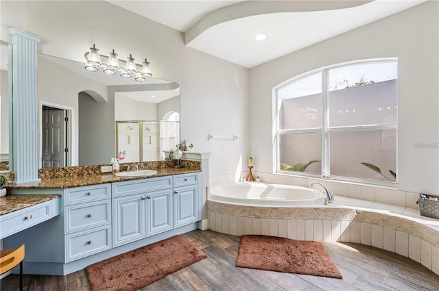 bathroom featuring wood-type flooring, vanity, and plus walk in shower