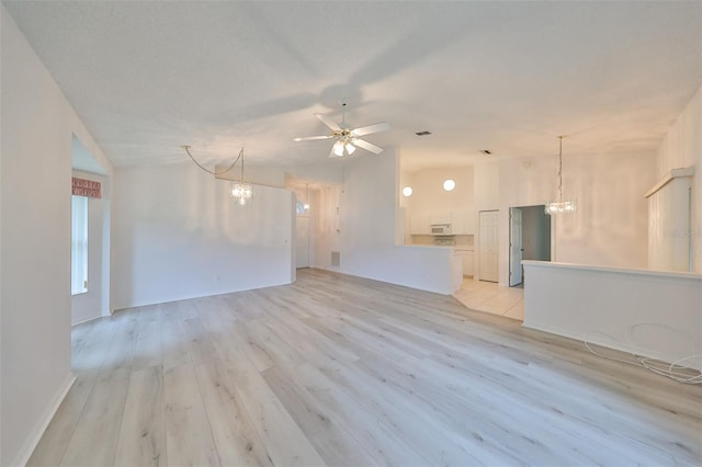 unfurnished living room with vaulted ceiling, light hardwood / wood-style flooring, and ceiling fan with notable chandelier