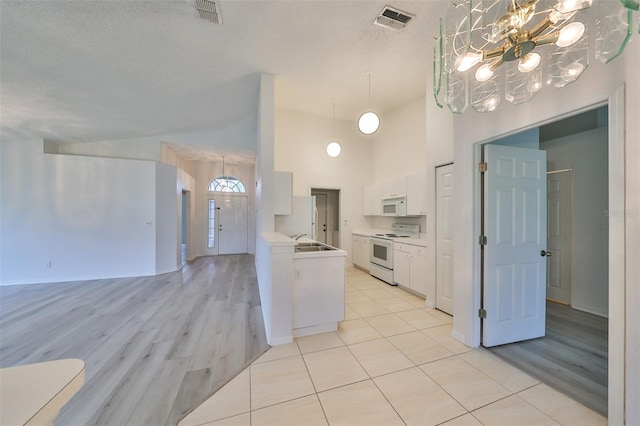 kitchen with white appliances, sink, light tile patterned flooring, white cabinetry, and a chandelier