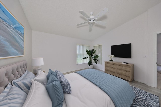 bedroom with a textured ceiling, light wood-type flooring, vaulted ceiling, and ceiling fan