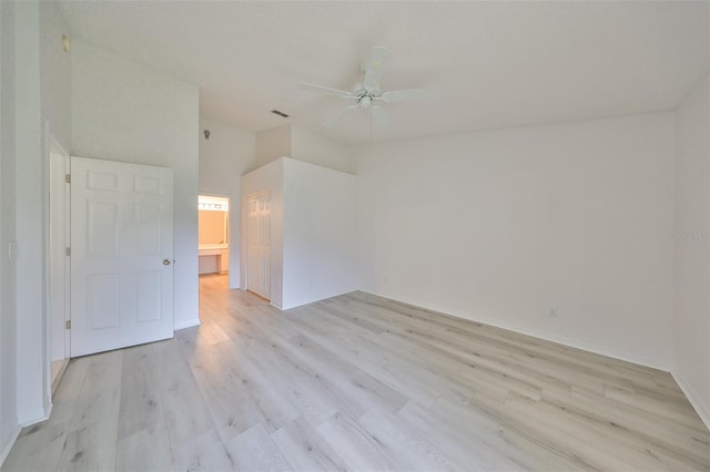 unfurnished room featuring ceiling fan, a towering ceiling, and light wood-type flooring