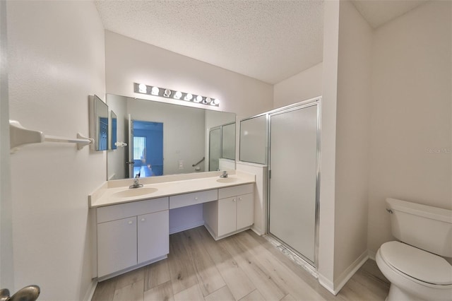 bathroom with hardwood / wood-style flooring, vanity, a textured ceiling, and walk in shower