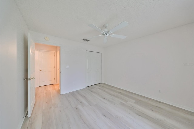 unfurnished room featuring a textured ceiling, light wood-type flooring, and ceiling fan