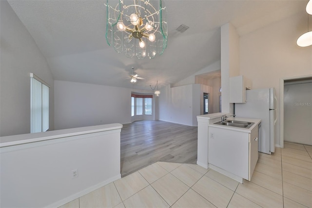 kitchen with white cabinets, ceiling fan with notable chandelier, lofted ceiling, and sink