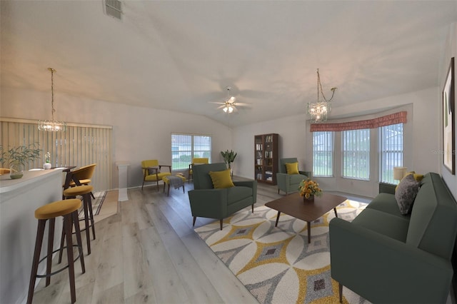 living room featuring ceiling fan with notable chandelier, light hardwood / wood-style floors, and vaulted ceiling