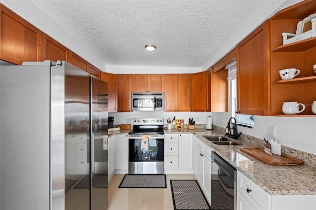 kitchen featuring light stone countertops, sink, a textured ceiling, white cabinets, and appliances with stainless steel finishes