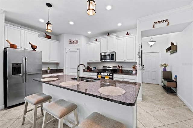 kitchen featuring appliances with stainless steel finishes, white cabinets, sink, and a center island with sink