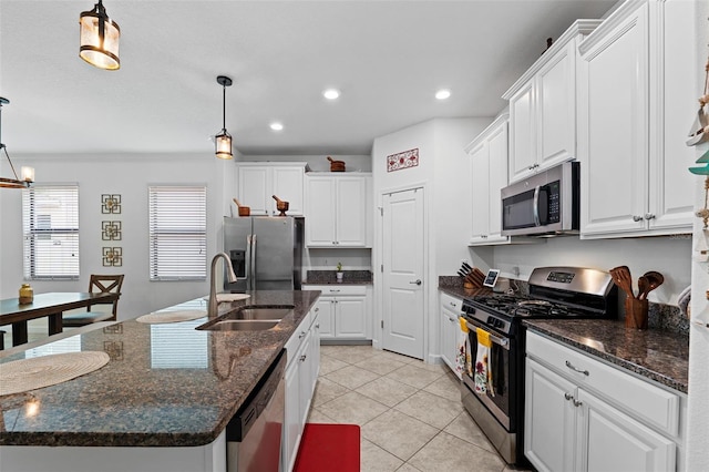 kitchen with appliances with stainless steel finishes, white cabinets, sink, and hanging light fixtures