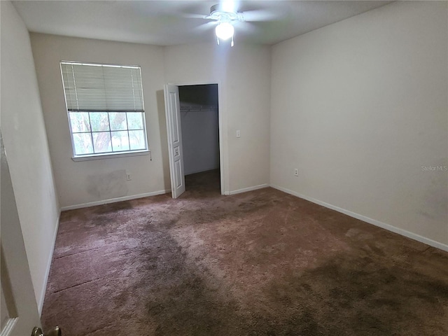 unfurnished bedroom featuring dark carpet, ceiling fan, and a closet